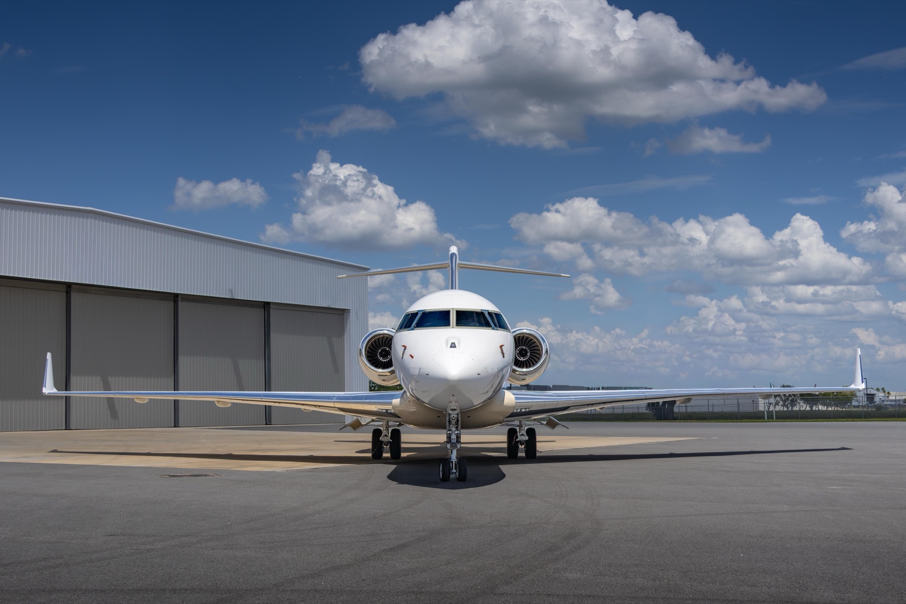 Bombardier Global 5000 nose-on in front of hangar with clouds