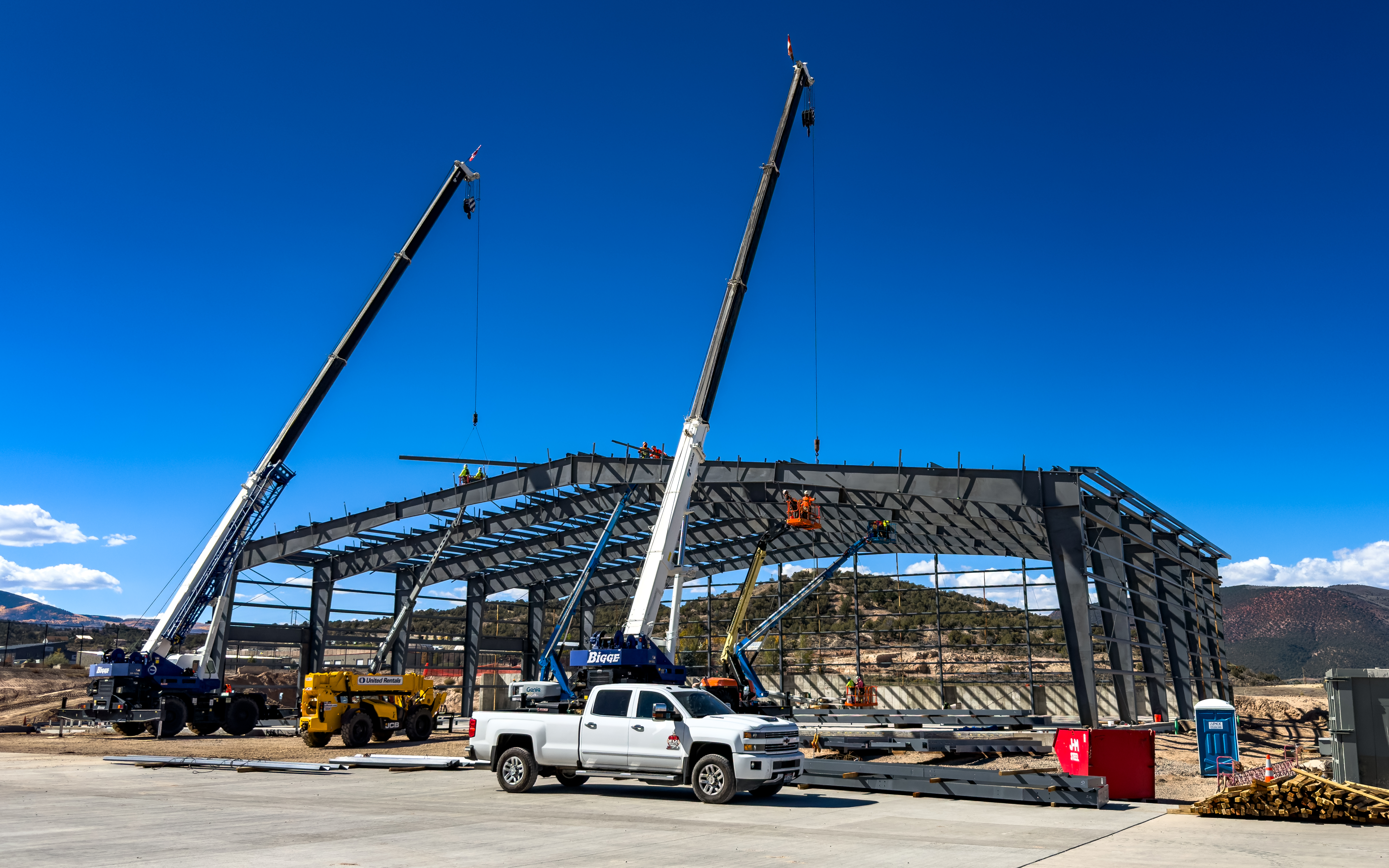 Aviation hangar under construction with cranes and mountain backdrop