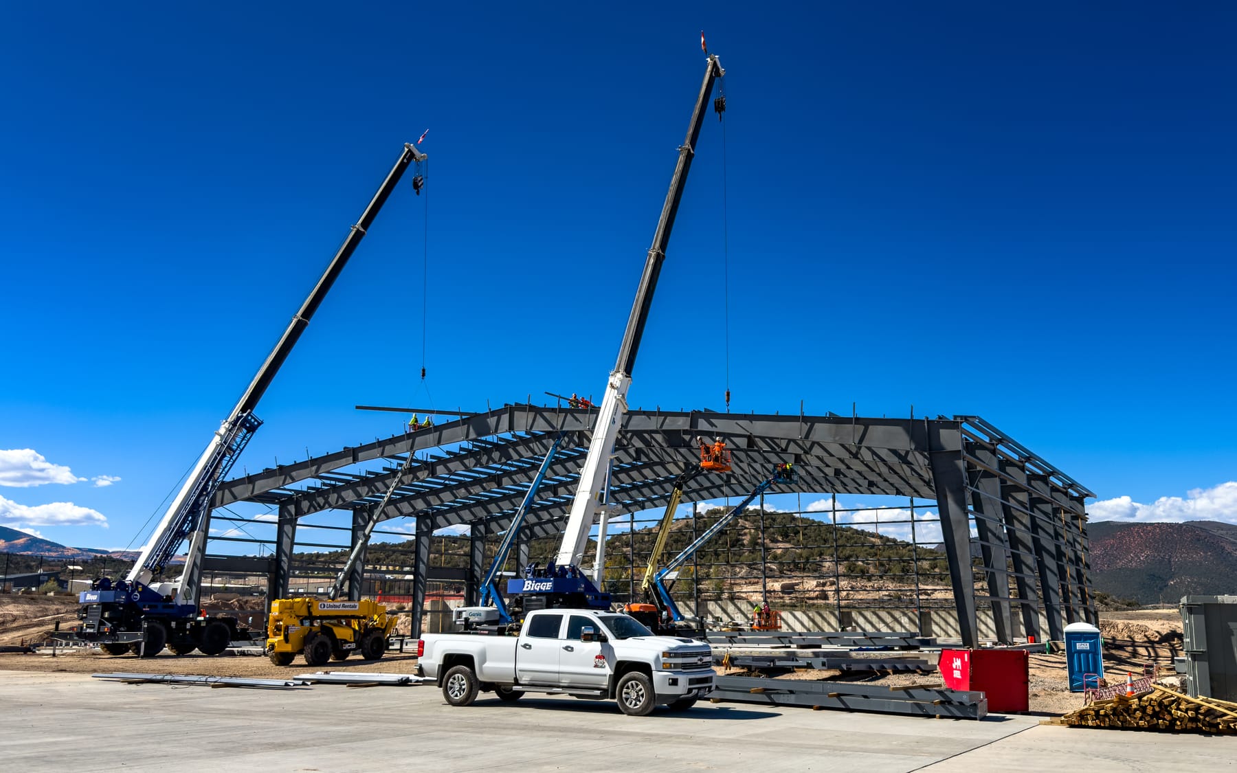 Aviation hangar under construction with cranes and mountain backdrop